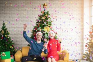 A man and woman sit in front of a Christmas tree celebrating plumbing tips